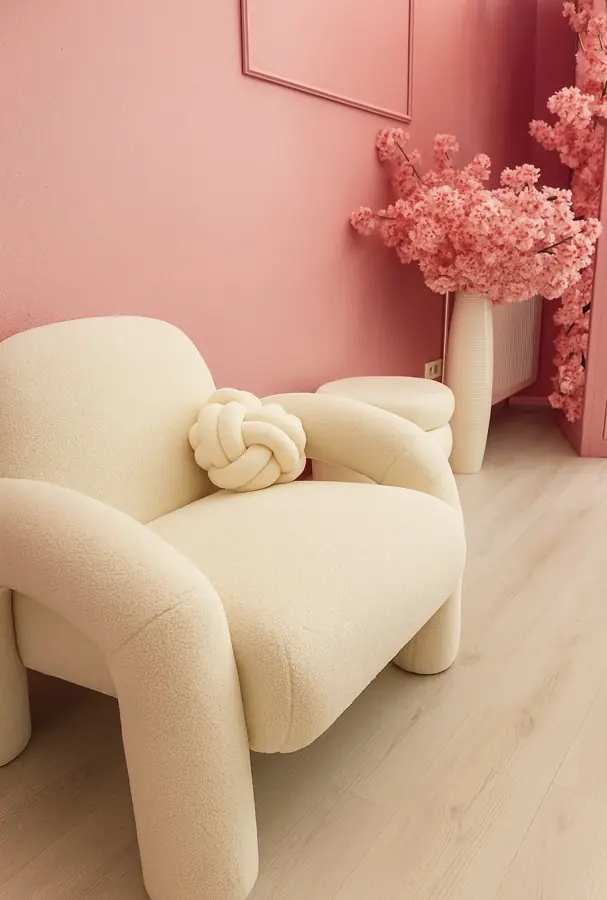 Cremefarbener Sessel vor rosa Wand